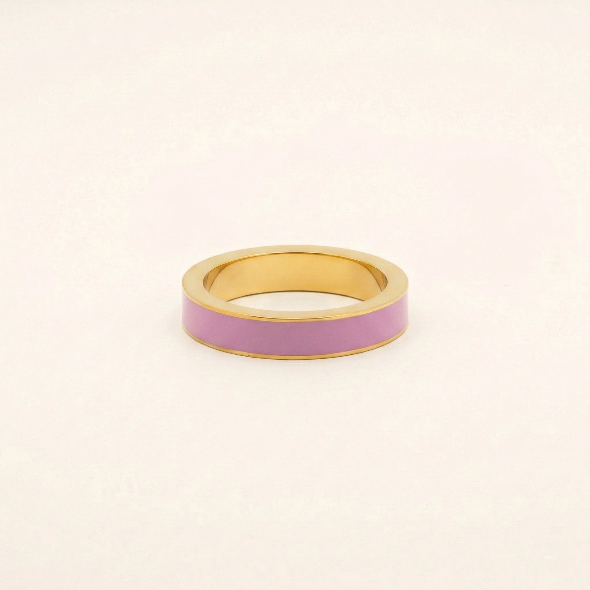 Gold ring with a pink band on a beige background